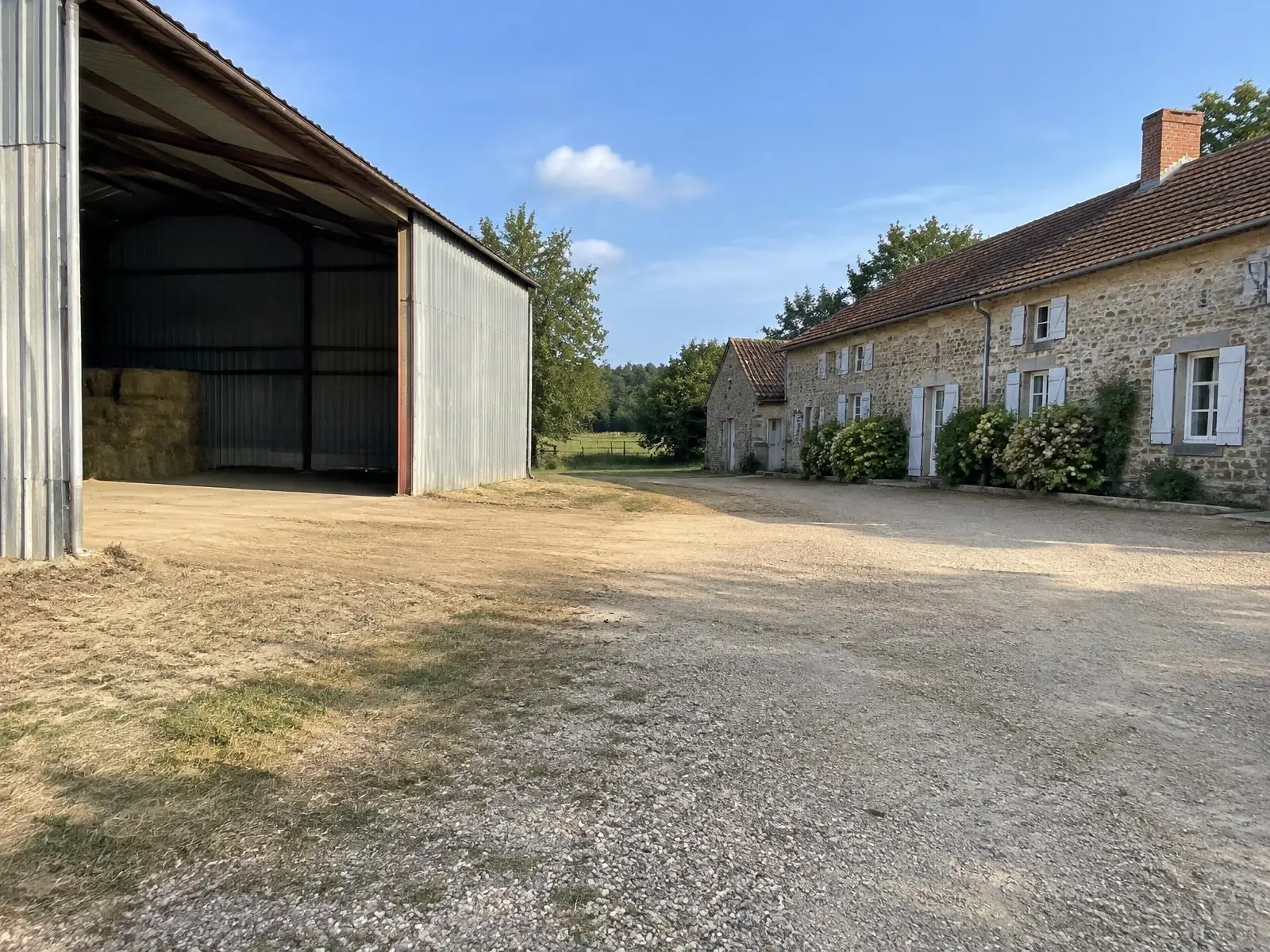La même cour dégagée : gravier propre devant le hangar ouvert, plus aucune ferraille.